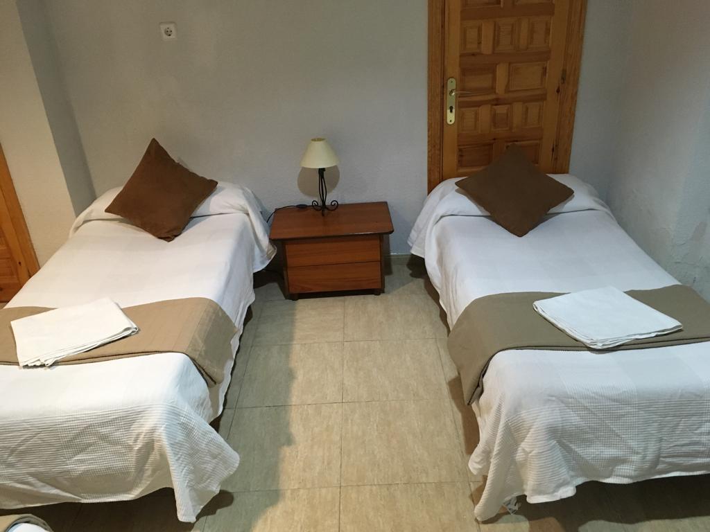 Habitación con dos camas individuales y una mesilla entre ellas.