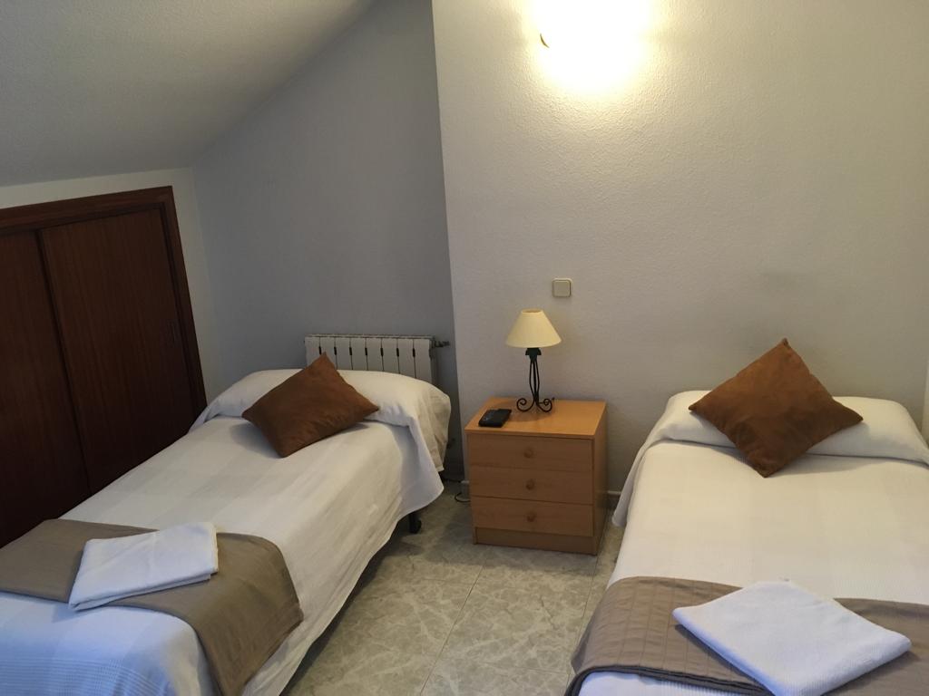 Habitación con dos camas individuales, mesilla y armario.